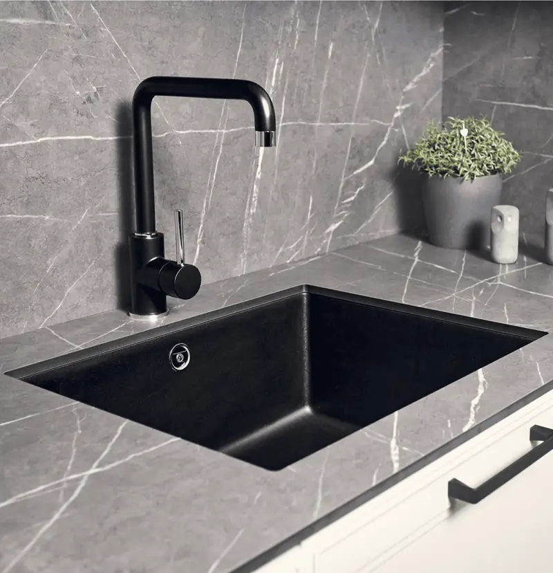 Un piano cucina in laminato effetto pietra grigia con un lavello nero.